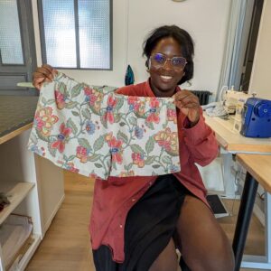 une jeune femme souriante montre le boxer short à motifs floraux qu'elle a réalisé de ses mains lors de la journée couture chez Re Up Circle à Nantes