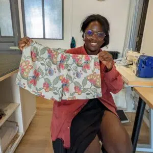 une jeune femme souriante montre le boxer short à motifs floraux qu'elle a réalisé de ses mains lors de la journée couture chez Re Up Circle à Nantes