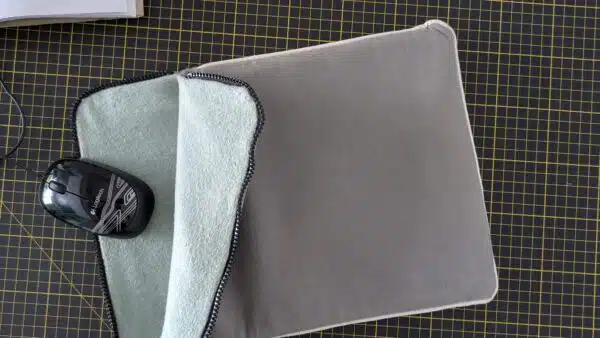 une housse d'ordinateur en tissu upcyclés (extérieur toile de bâche grise, intérieur sweat jersey retourné vert) chez Re Up Circle Nantes